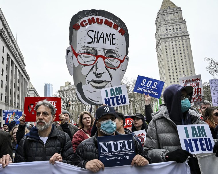 Un manifestant tient une coupure du sénateur Chuck Schumer