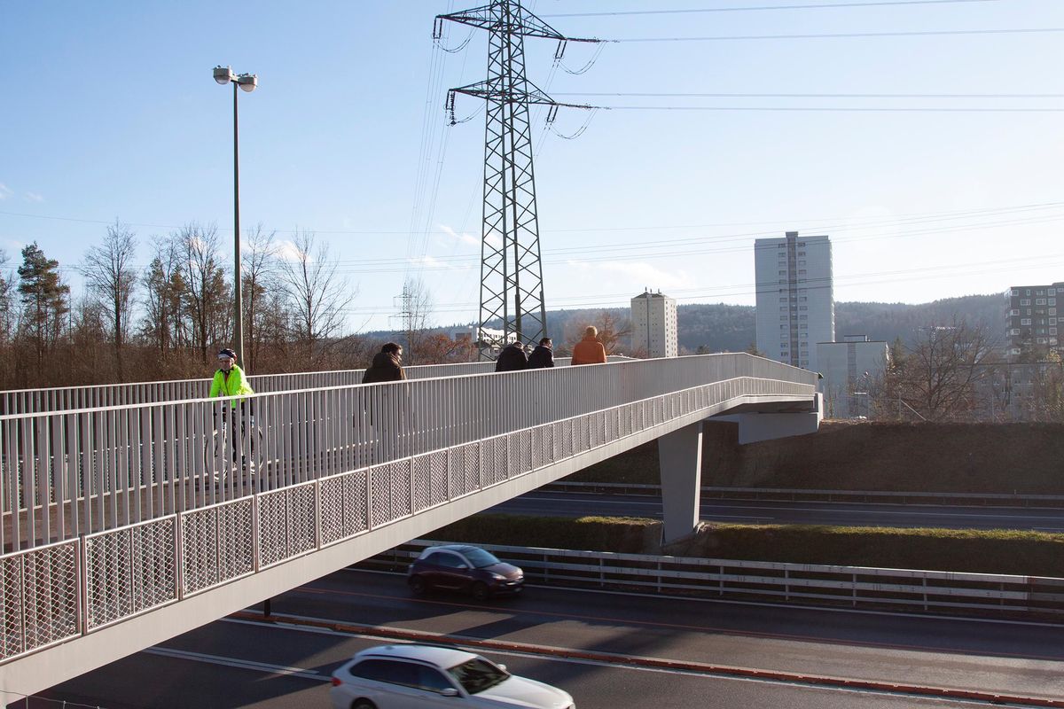 Passerelle piétonne surplombant une route à fort trafic, avec des personnes marchant sur la passerelle.