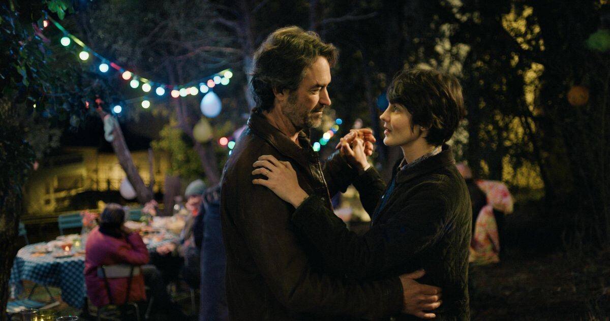 Deux personnes dansent sous des lumières colorées lors d’une fête en plein air le soir.