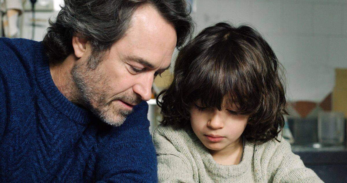 Un homme à la barbe grisonnante et un enfant aux cheveux bouclés examinent attentivement quelque chose hors champ.