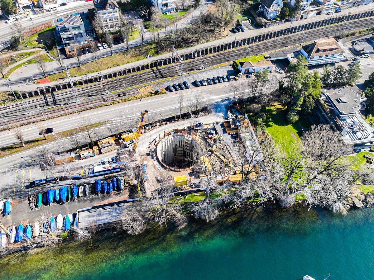 Aerial view of the construction site for the energy network Lengg on the Wässerigwiese in Zollikon/Tiefenbrunnen, surrounded by railway tracks and boats at the lakeside.