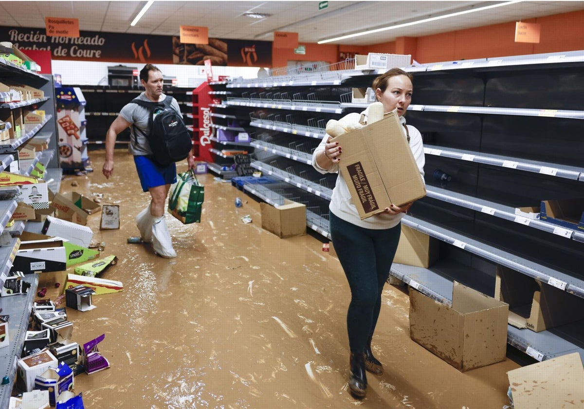 Empleados de un comercio afectado por la dana en la provincia de Valencia limpian el establecimiento inundado