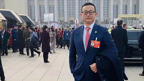 Yang Tengbo standing in front of the Great Hall of the People, Beijing, China