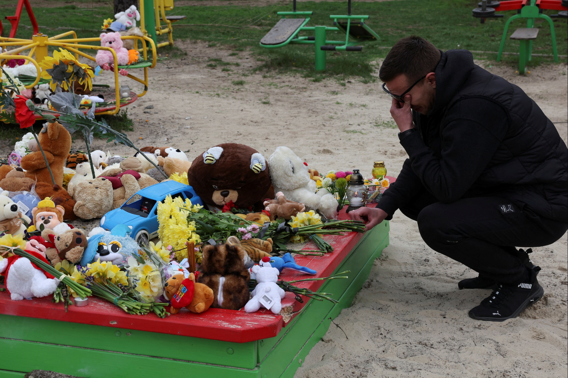 Un homme en larmes dépose des fleurs près d'une aire de jeux à Kryvyj Rih