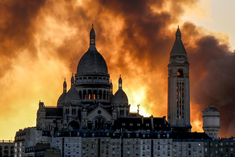 Un nuage de fumée derrière la basilique du Sacré-Cœur alors qu'un important incendie s'est déclaré dans le 17e arrondissement, dans le nord de Paris, le 7 avril 2025.