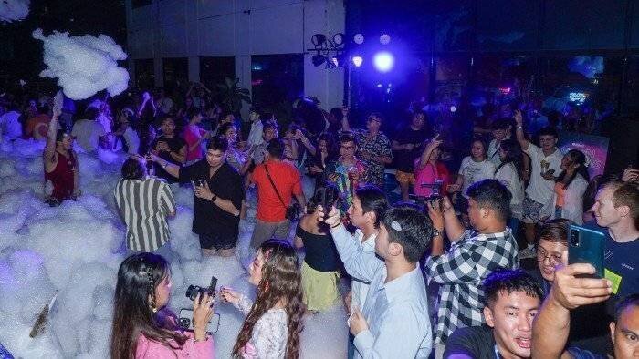 Une fête d'entreprise avec des gens dansant et prenant des photos sous des lumières colorées