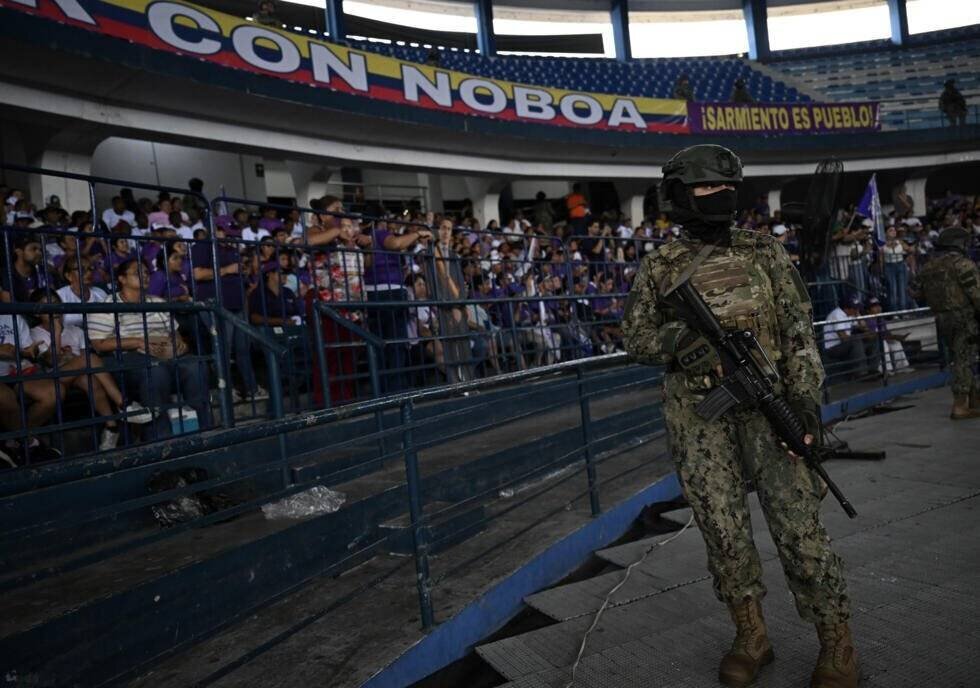 Un militaire monte la garde alors que des partisans du président et candidat à la présidence, Daniel Noboa, attendent le début de son meeting de clôture de campagne à Guayaquil, le 10 avril 2025 en Équateur
