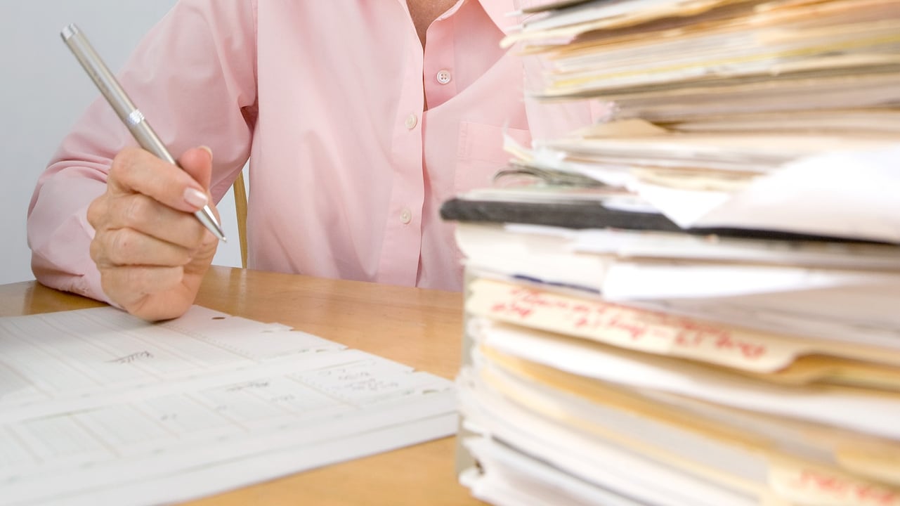Une femme âgée assise devant une pile de documents