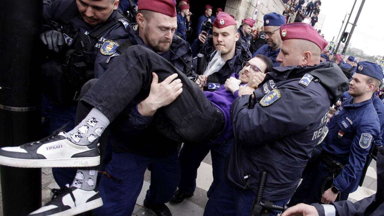 Police hongroise retirant un manifestant bloquant l'entrée du bâtiment du Parlement à Budapest le 14 avril 2025.
