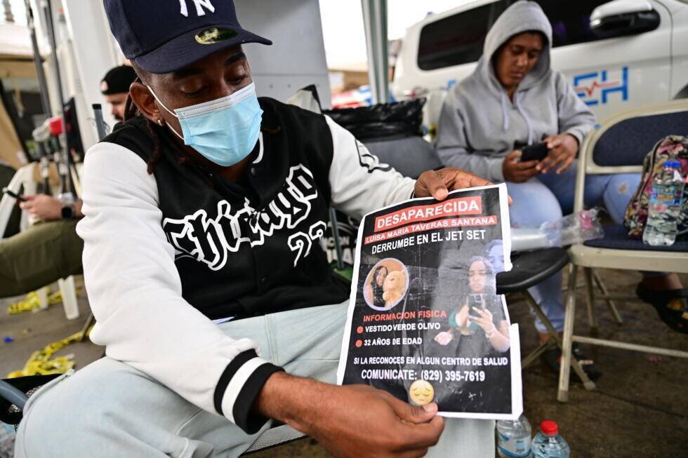Un homme montre une photo d'une proche dont il attend des nouvelles à l'extérieur de la discothèque