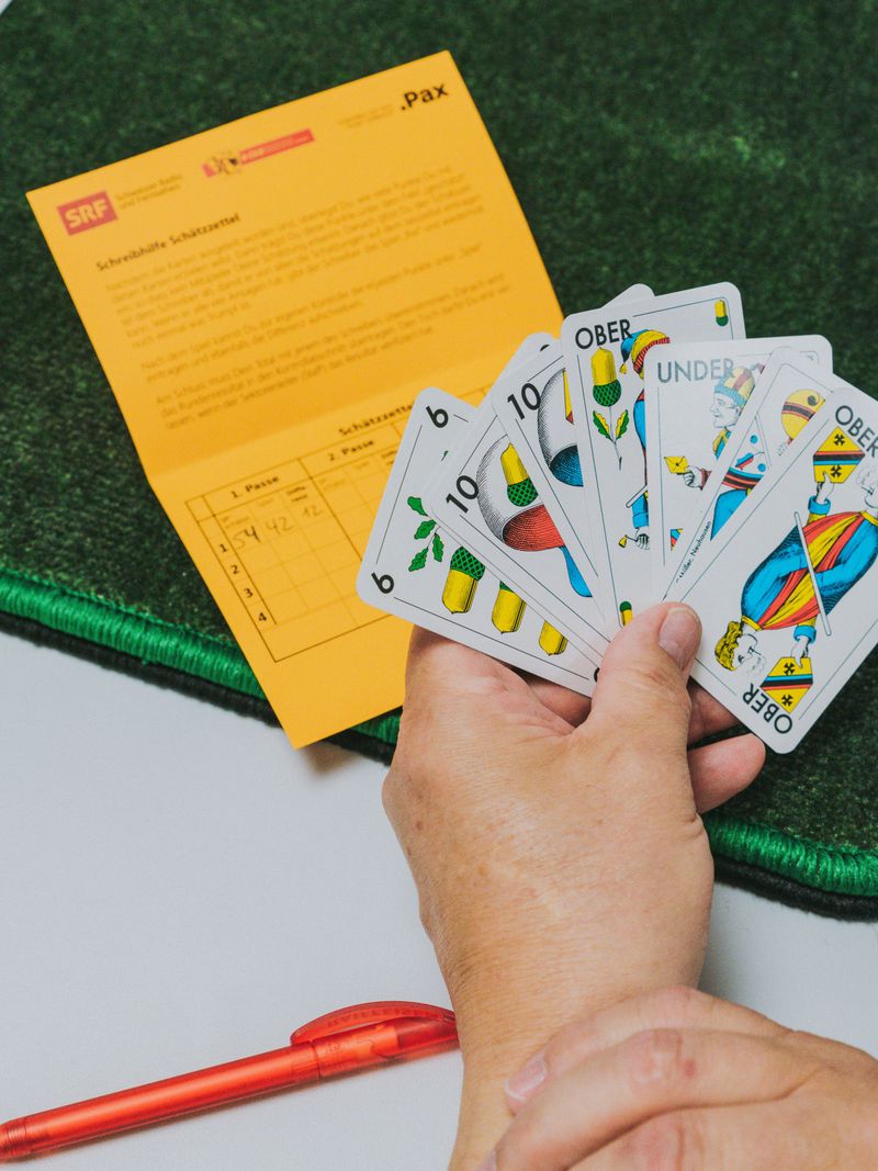 Main tenant des cartes de Jass sur une table verte