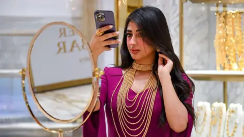 Femme essayant un collier en or au salon ASJAD à Doha, Qatar