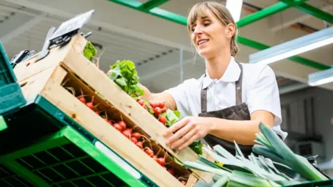 Femme triant des légumes dans un supermarché