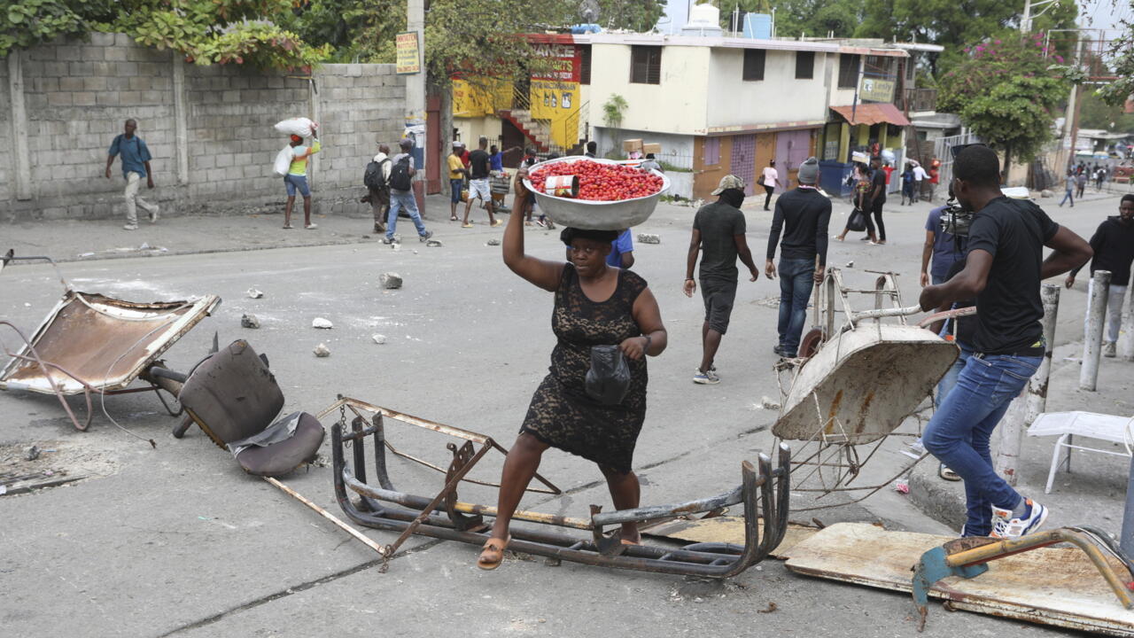 Un vendeur ambulant franchit une barricade érigée par des manifestants protestant contre l'insécurité, à Port-au-Prince, Haïti, le mercredi 16 avril 2025.
