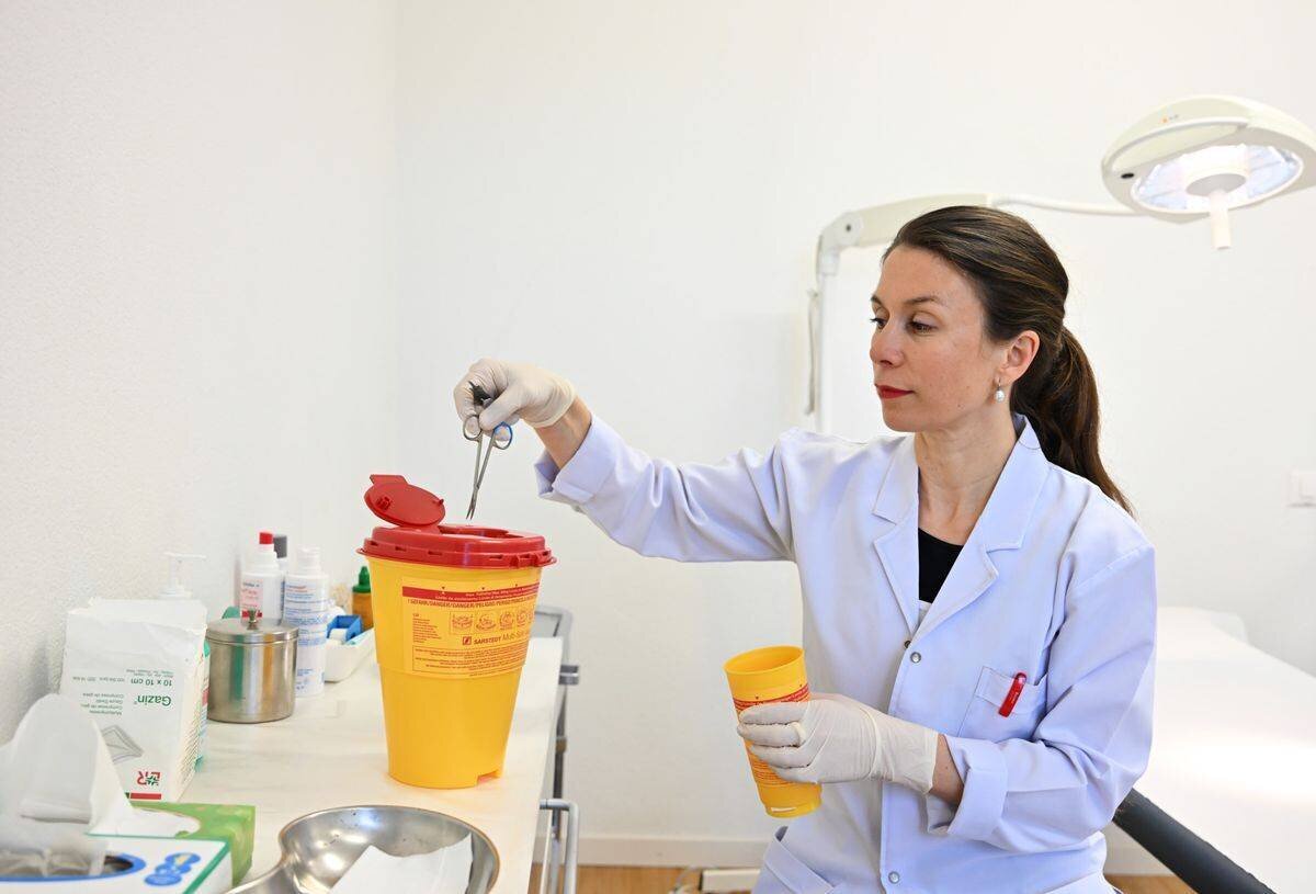 Dermatologue Katrin Baumann Conzett jetant un instrument médical jetable dans son cabinet