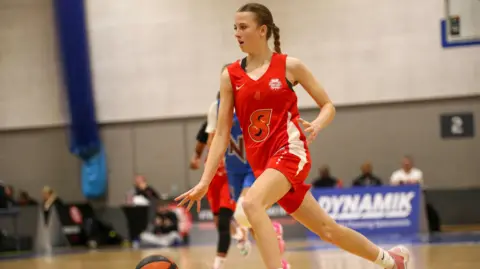 Jess, 15 ans, jouant au basket lors d’un tournoi compétitif