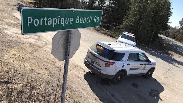 Panneau routier de la route Portapique Beach et deux véhicules de police qui bloquent l'entrée de la route.