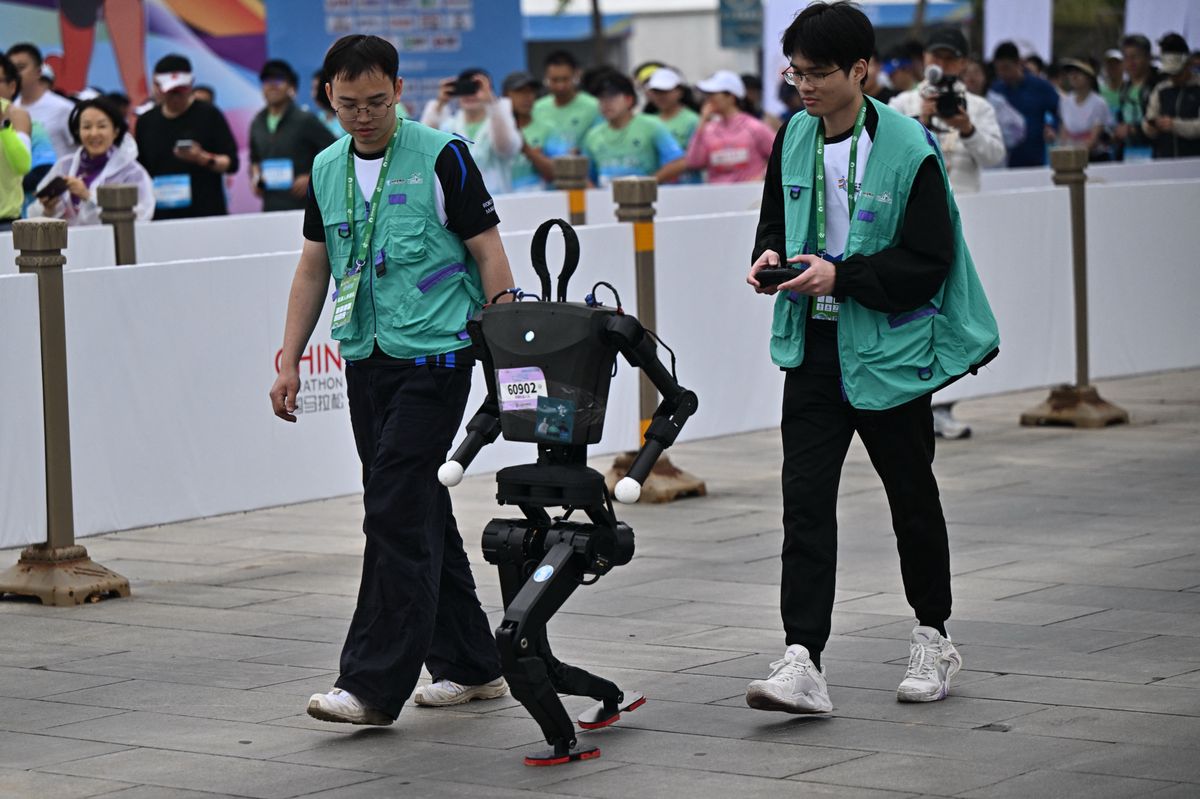 Un robot humanoïde participe à un semi-marathon à Pékin, accompagné de deux assistants humains, lors de l’événement du 19 avril 2025, illustrant la technologie avancée de la Chine.