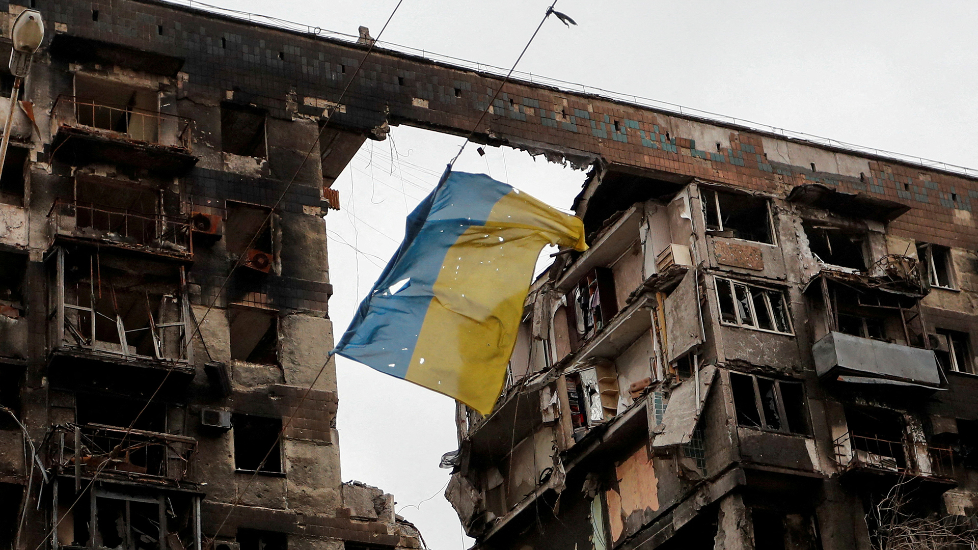 Drapeau ukrainien déchiré devant un immeuble détruit à Marioupol