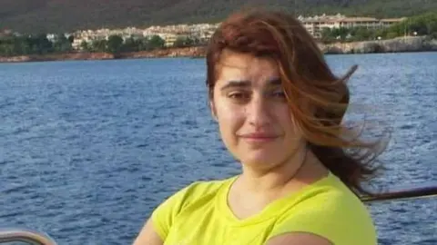 Lina, assise dans un bateau devant la mer, portant un t-shirt jaune