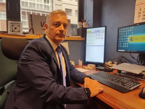 Homme assis à un bureau devant un ordinateur