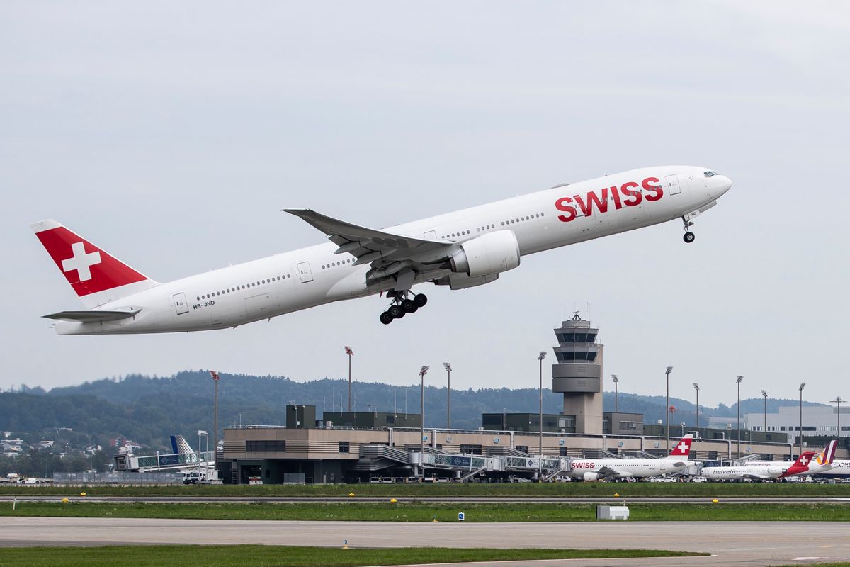 Une Boeing 777-300 de Swiss décolle à Zurich, avec la tour de contrôle en arrière-plan