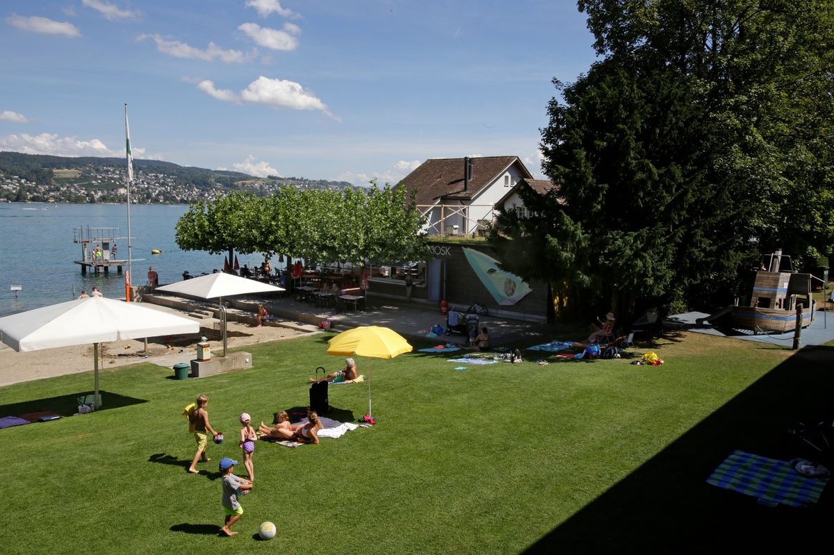Espace vert à la baignade de Rüschlikon avec des personnes se relaxant à côté du kiosque