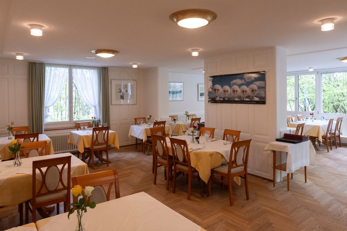 Intérieur du restaurant Muggenbühl à Zürich avec tables dressées et ambiance lumineuse et accueillante.