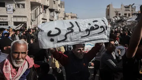 Manifestation anti-Hamas à Gaza avec un homme âgé en premier plan tenant une pancarte 'Stop the war'