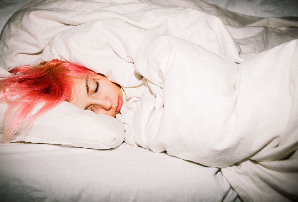Adolescente dormant sous une couverture blanche