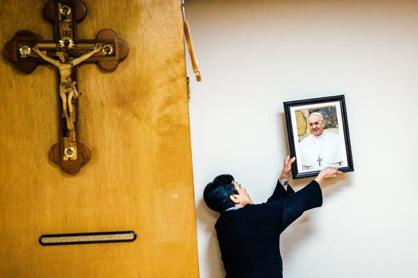 Mayra Rossell accroche un portrait du pape François au mur de l'église catholique Saint Martha à Miami