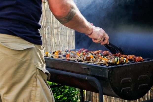 Homme grillant des brochettes sur un barbecue