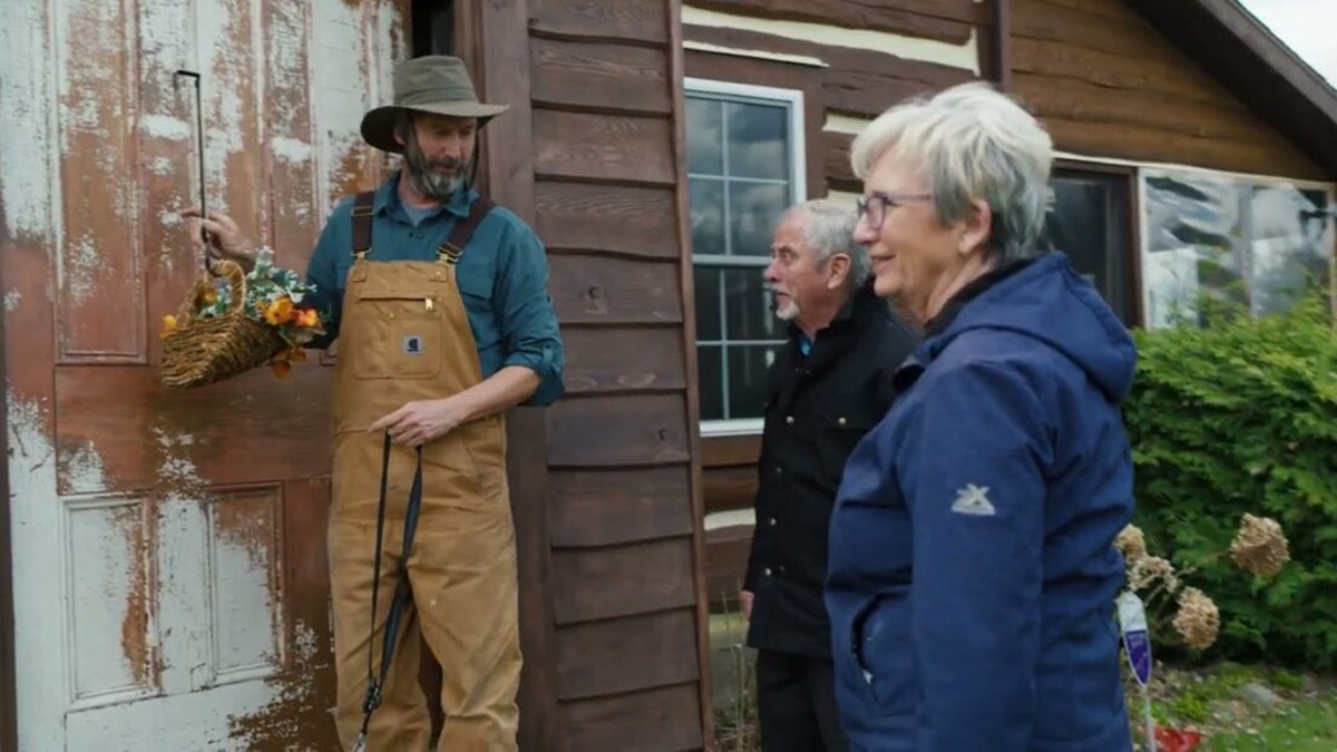 Tom Green montrant une affiche sur sa porte à ses parents.