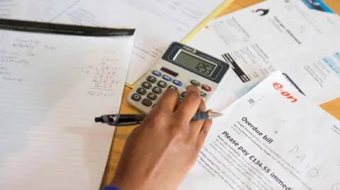 Une femme calcule ses factures d'énergie avec une calculatrice