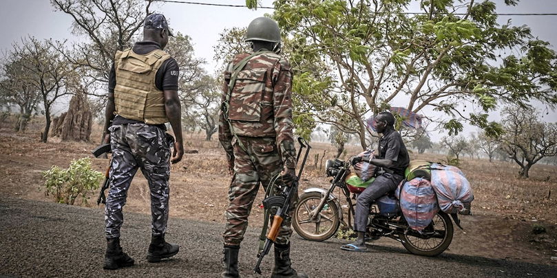 Un policier et un soldat béninois contrôlent un motard à un point de contrôle près de Porga, au nord du pays, zone touchée par plusieurs attaques djihadistes ces dernières années. Le Bénin, frontalier du Burkina Faso et du Niger, subit de plein fouet l’expansion des violences liées à Al-Qaïda et à l’État islamique, amplifiées par les reconfigurations géopolitiques au Sahel.