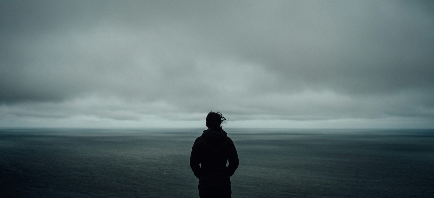 Personne en hoodie dos à un ciel nuageux
