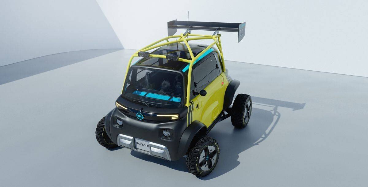 Ein futuristisches Micro-Mobil mit sportlichem Design und breitem Aufbau, ausgestattet mit einem grossen Heckspoiler, in einer hellen Umgebung.