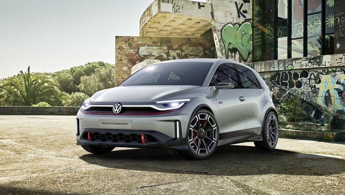 Der VW ID.GTI parkt vor einer von Graffitis bedeckten Wand, umgeben von grüner Landschaft.