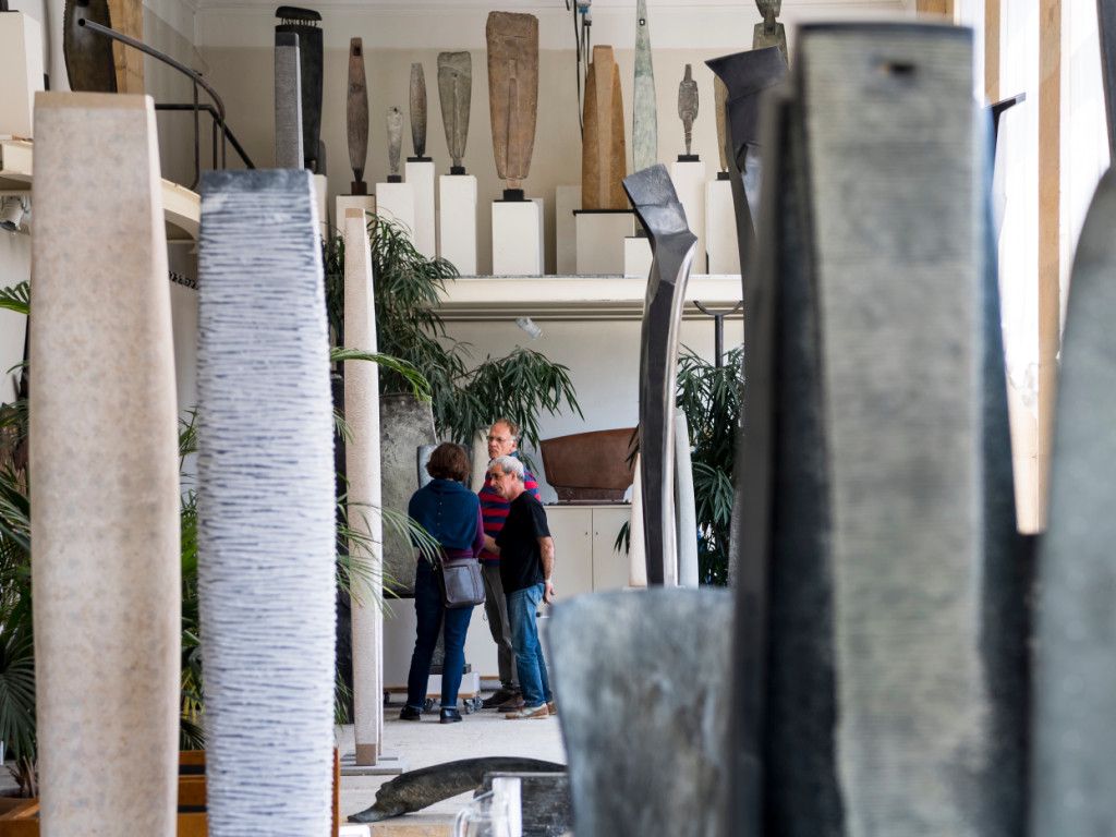 Des visiteurs explorent l’atelier du sculpteur Yves Dana à Lausanne, entourés de sculptures modernes, lors de l’événement APERTI.