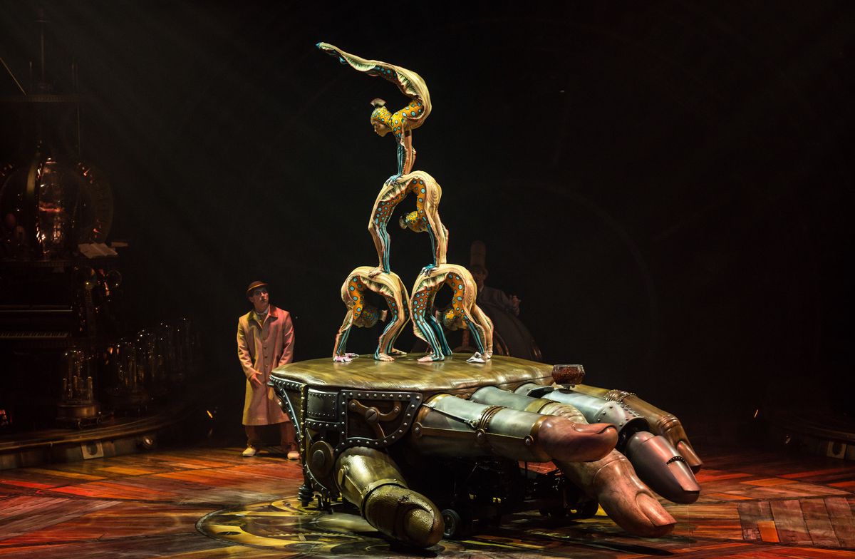 Des artistes acrobatiques exécutent une pyramide humaine sur une grande main mécanique lors d’un spectacle.