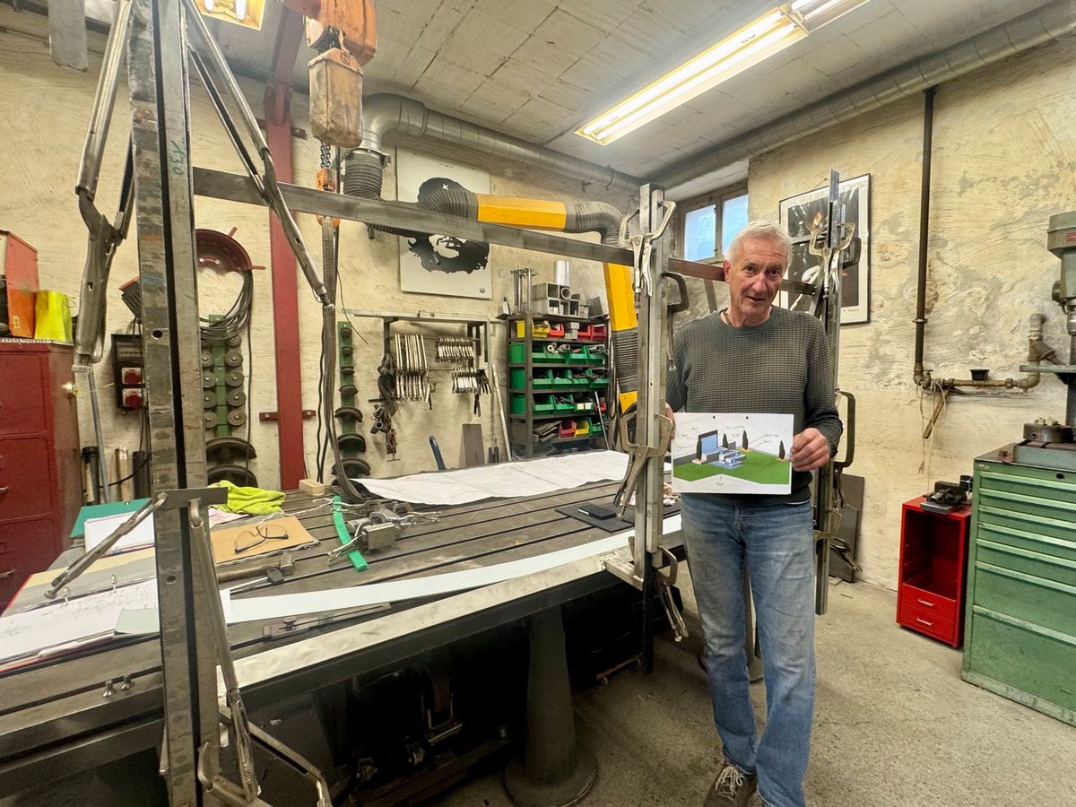Röbi Rahm dans son atelier, tenant une photo, entouré d'outils et machines