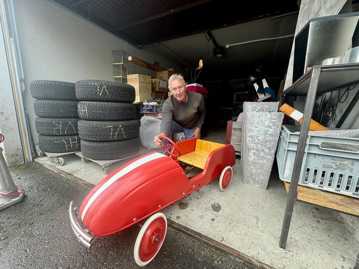 Röbi Rahm répare un jouet à pédales rouge dans son garage, entouré de pneus