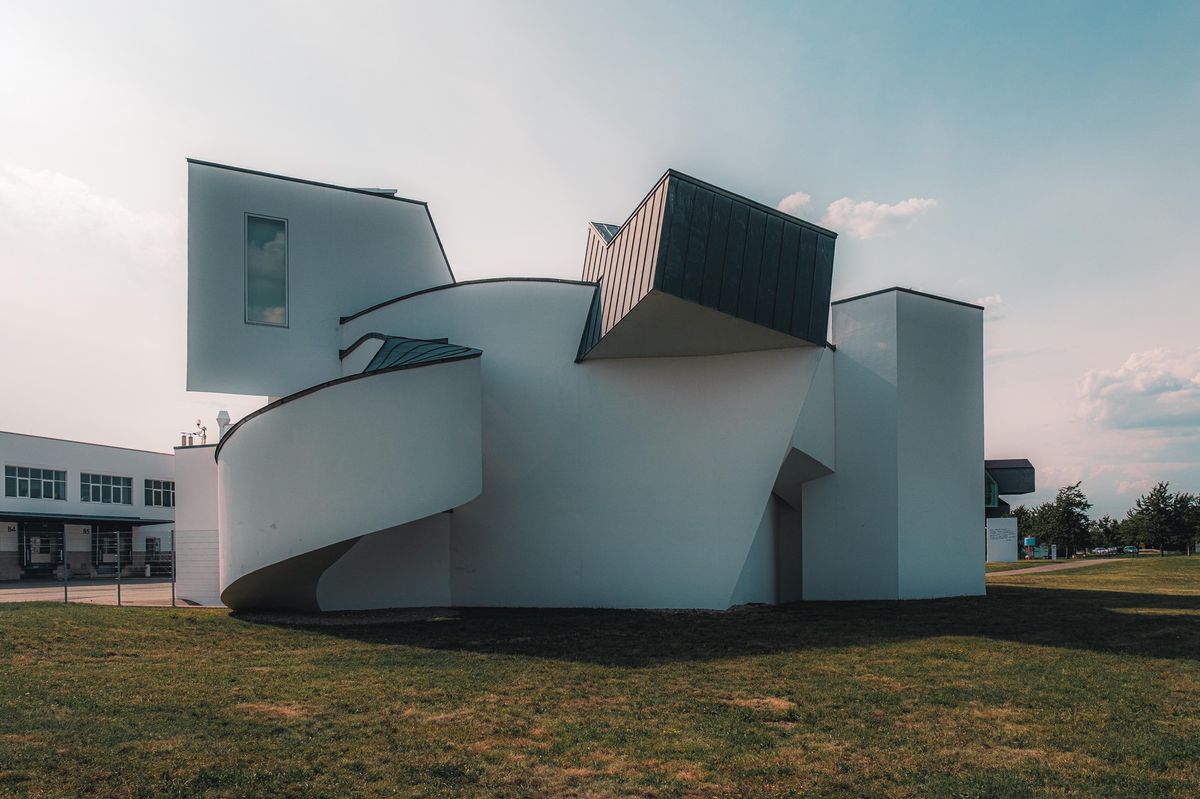 Bâtiment moderne au design architectural innovant avec des formes géométriques uniques et des murs blancs sur un fond de ciel bleu.