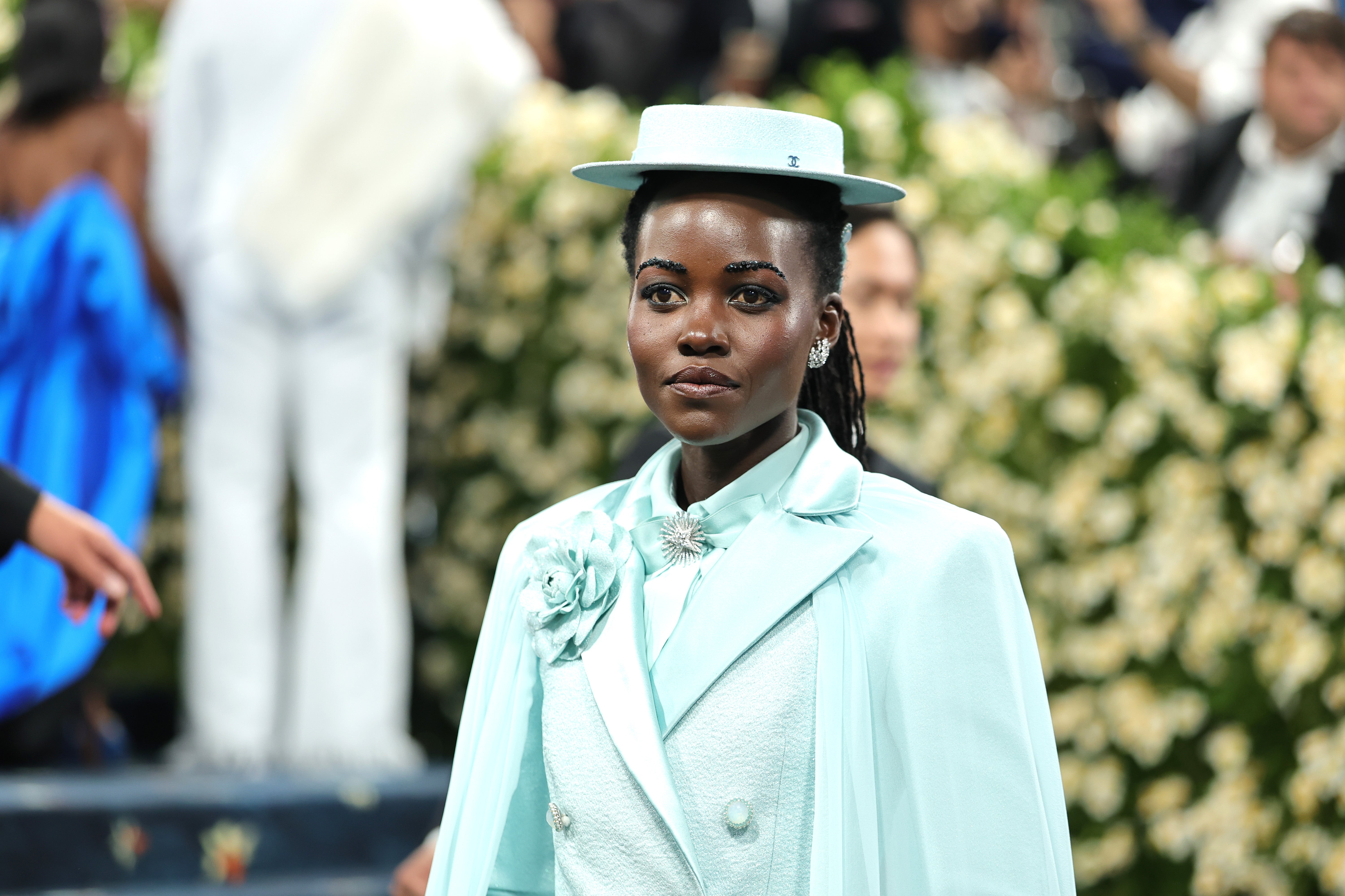 Lupita Nyong’o porte un chapeau haut et ses sourcils ornés de bijoux
