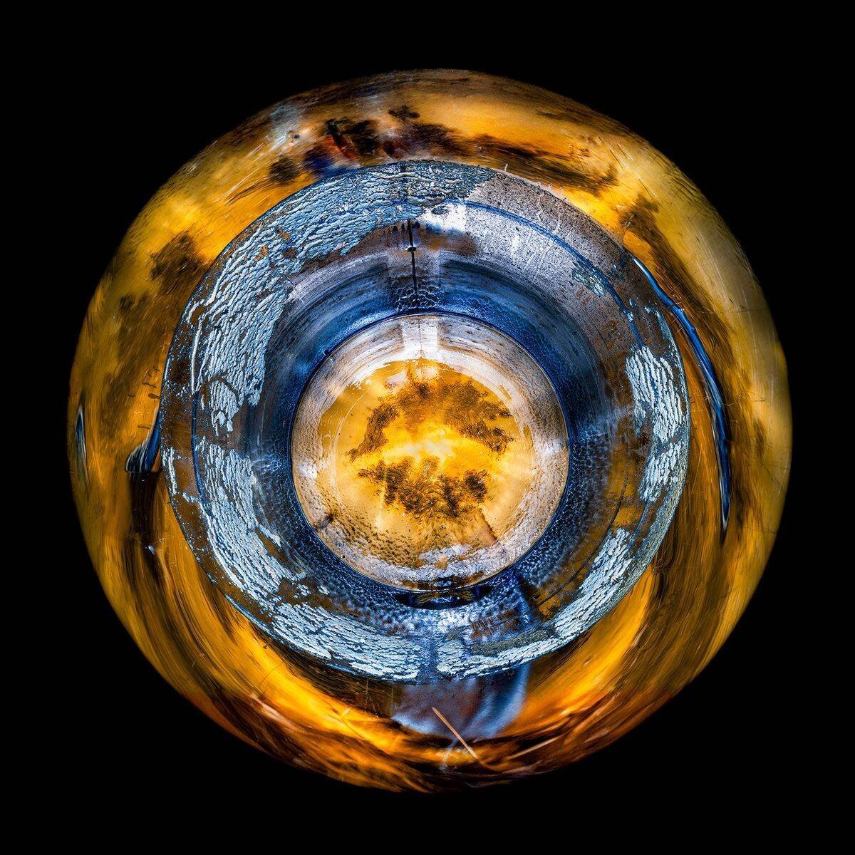 Image artistique d’une sphère colorée en bleu, jaune et orange avec des motifs abstraits, sur fond noir.