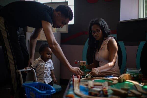 Trinity Chisholm et Xeno Carrington jouant avec leur fils d'un an dans une bibliothèque avec des jouets