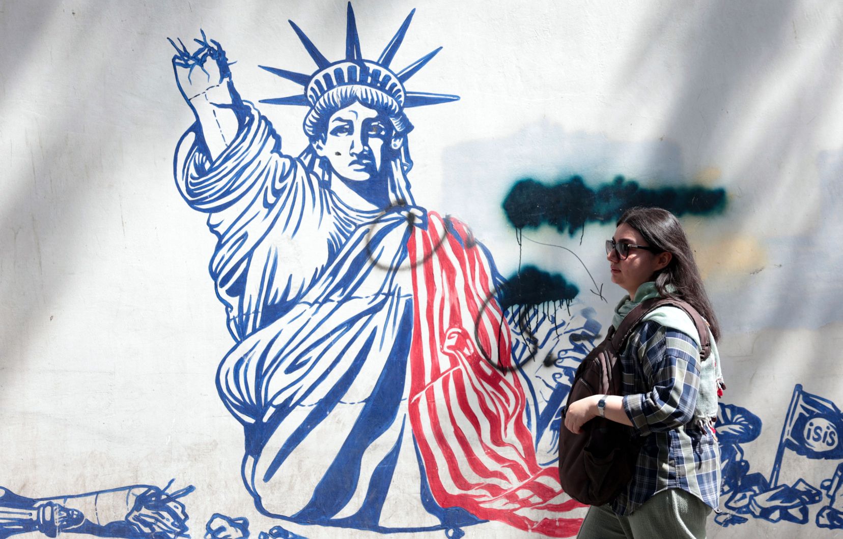 Une femme marche à côté d’une peinture murale anti-américaine près de l’ancienne ambassade américaine à Téhéran, le 11 mai 2025.