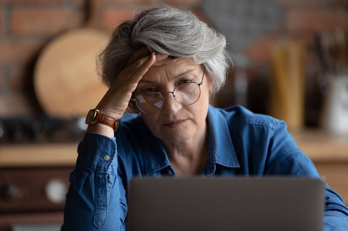 Personne frustrée posant la main sur la tête devant un ordinateur portable