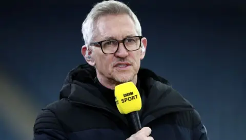 Gary Lineker sur un terrain de football, tenant un micro de BBC Sport en 2021