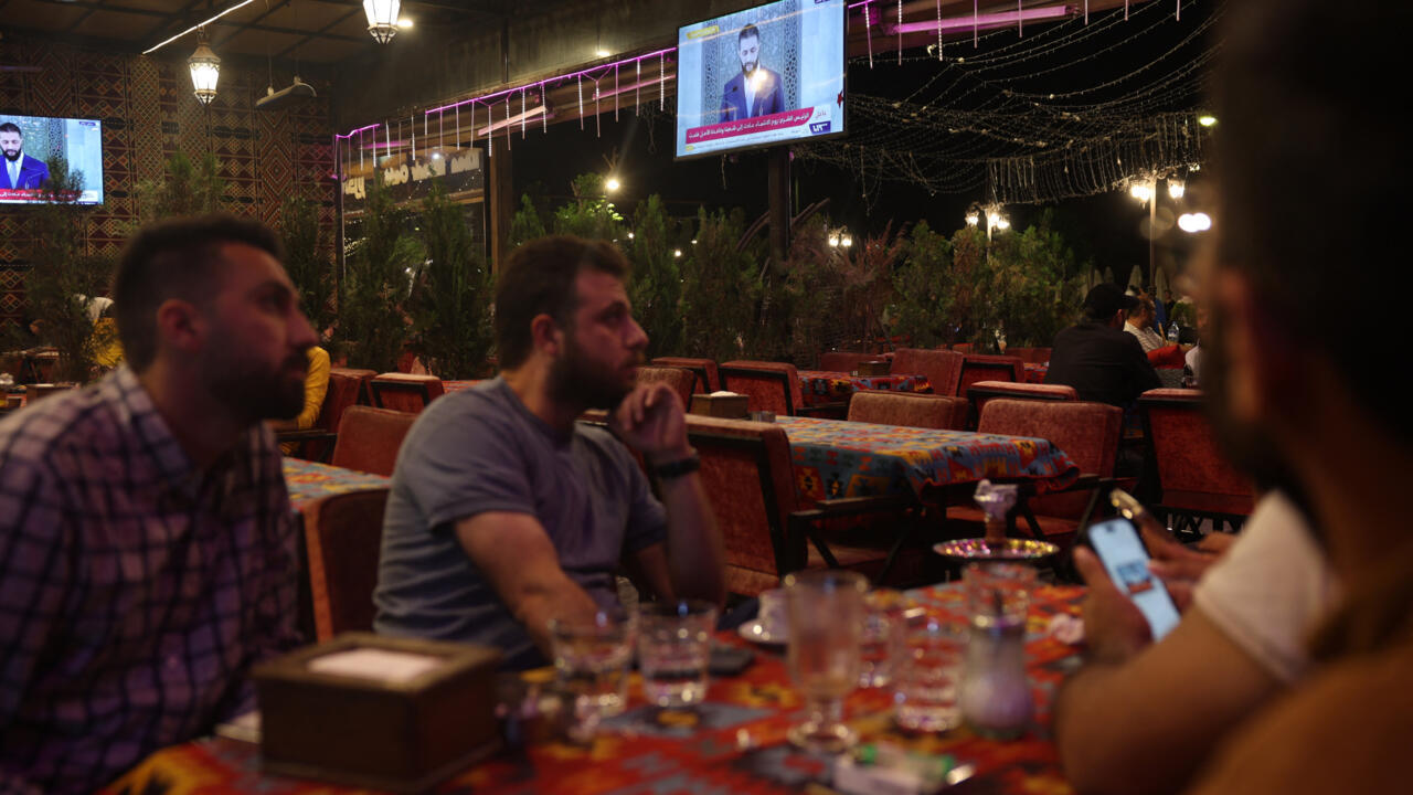 Syriens regardant un discours télévisé d'Ahmed al-Sharaa à Alep, mai 2025
